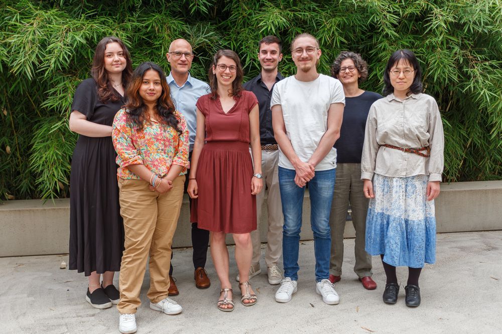 A group photo with eight people standing in front of a natural background.