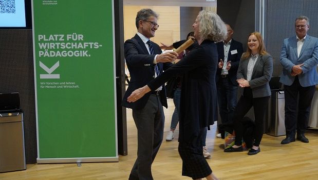 Prof. Neuweg hands the baton to Prof. Stock (University of Graz), hosts of the 2025 symposium; Photo credit: JKU