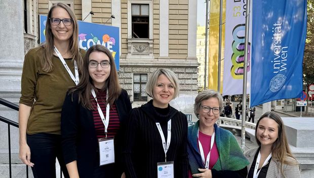 5 Frauen stehen auf der Stiege vor der TU Wien, im Hintergrund die Fahne mit dem Kongress-Logo