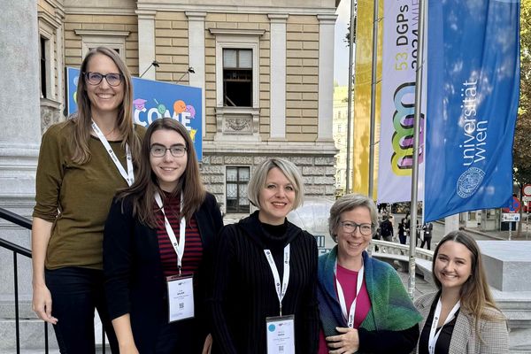 5 Frauen stehen auf der Stiege vor der TU Wien, im Hintergrund die Fahne mit dem Kongress-Logo