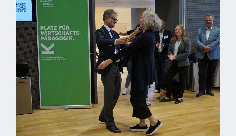 Prof. Neuweg hands the baton to Prof. Stock (University of Graz), hosts of the 2025 symposium; Photo credit: JKU